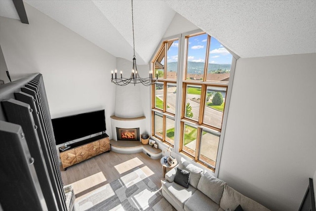 340 Fairway Dr, Spearfish, SD 57783 - living area with lofted ceiling, wood finished floors, a chandelier, a textured ceiling, and a lit fireplace