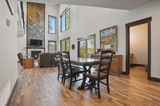 21332 Trailside Rd, Lead, SD 57754 - dining room featuring light wood-style floors, a fireplace, and a high ceiling