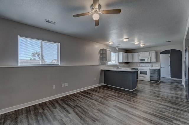 212 E Custer St, Rapid City, SD 57701 - kitchen featuring white appliances, a peninsula, a ceiling fan, arched walkways, and a textured ceiling