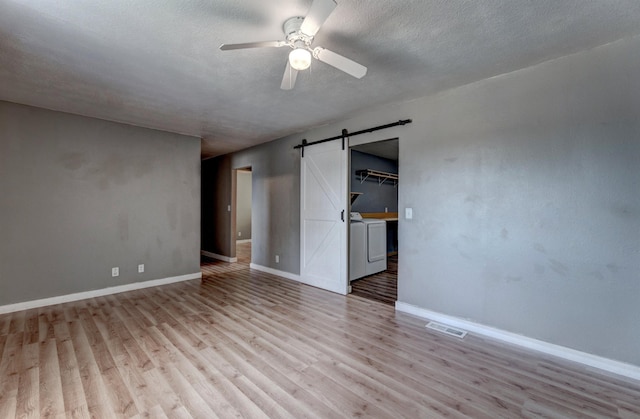 212 E Custer St, Rapid City, SD 57701 - spare room featuring a barn door, ceiling fan, light wood-style flooring, a textured ceiling, and washing machine and clothes dryer