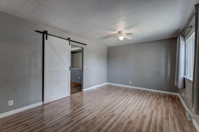 212 E Custer St, Rapid City, SD 57701 - unfurnished bedroom with a barn door, wood finished floors, a ceiling fan, and a textured ceiling