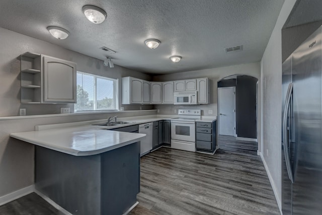 212 E Custer St, Rapid City, SD 57701 - kitchen with white appliances, a peninsula, dark wood-type flooring, a textured ceiling, and arched walkways
