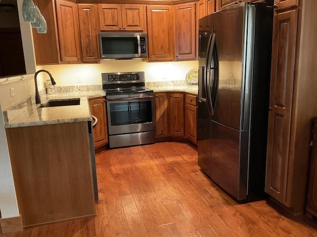 772 Stage Run Rd, Deadwood, SD 57732 - kitchen featuring stainless steel appliances, brown cabinets, light wood-type flooring, and light stone countertops