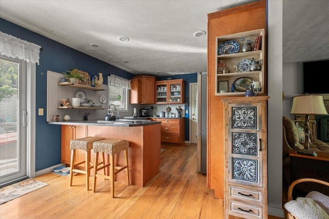 10 Crescent Dr, Deadwood, SD 57732 - kitchen featuring brown cabinetry, open shelves, a breakfast bar area, light wood-style floors, and healthy amount of natural light