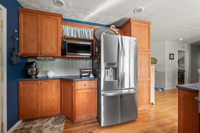 10 Crescent Dr, Deadwood, SD 57732 - kitchen featuring appliances with stainless steel finishes, light wood-style floors, brown cabinetry, and dark countertops