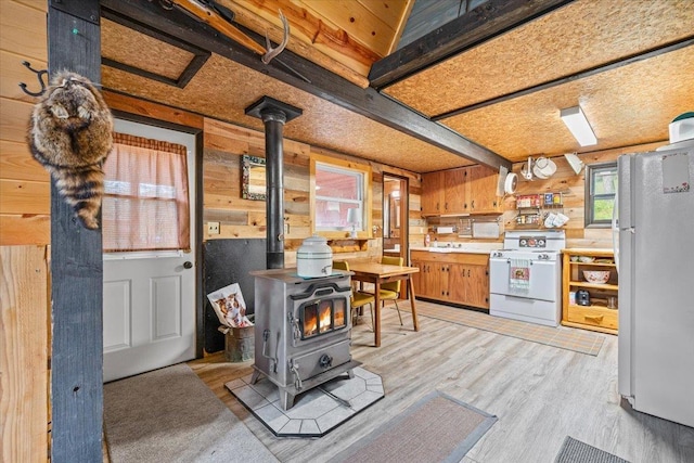 12425 Misty Ln, Nemo, SD 57759 - kitchen featuring a wood stove, white appliances, wood walls, light countertops, and light wood-type flooring
