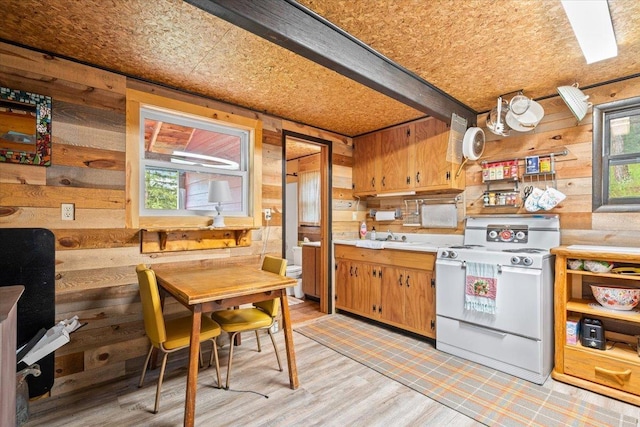 12425 Misty Ln, Nemo, SD 57759 - kitchen with white range with electric stovetop, wood walls, light countertops, brown cabinetry, and light wood finished floors