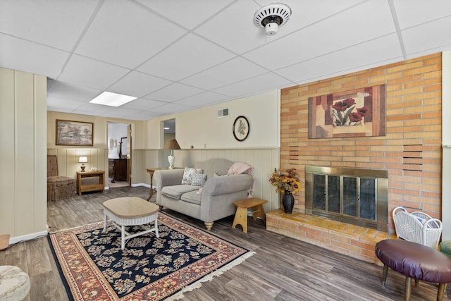 4103 W Main St, Rapid City, SD 57702 - living area with a drop ceiling, a brick fireplace, wood finished floors, and a wainscoted wall