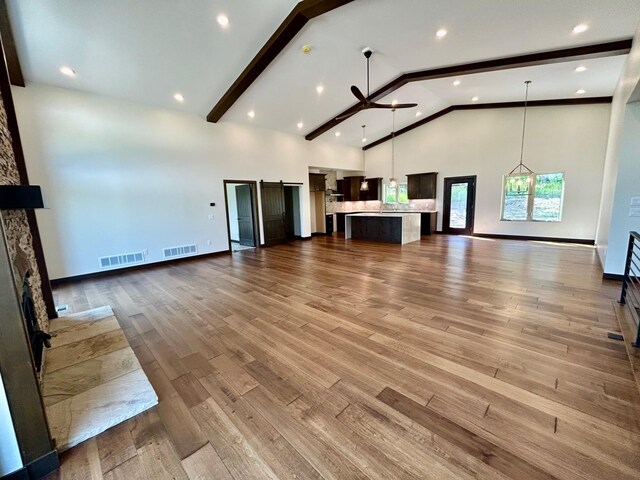 25809 Sidney Trl, Custer, SD 57730 - unfurnished living room featuring high vaulted ceiling, a ceiling fan, wood finished floors, beamed ceiling, and a fireplace