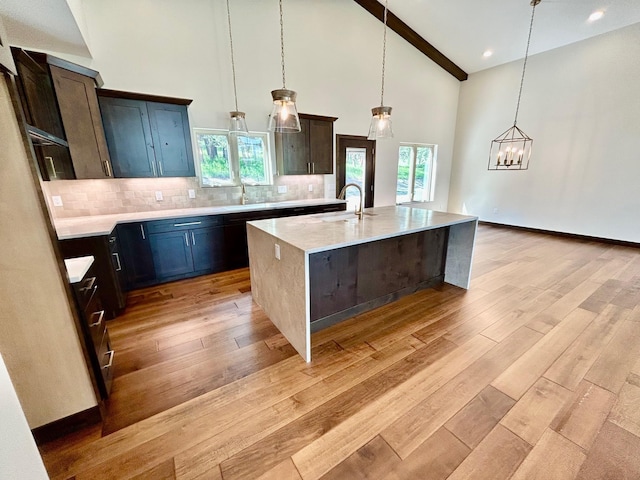 25809 Sidney Trl, Custer, SD 57730 - kitchen with light wood finished floors, high vaulted ceiling, backsplash, a chandelier, and an island with sink