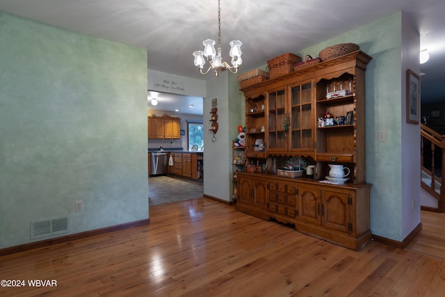 unfurnished dining area with wood-type flooring and a chandelier