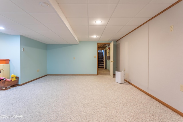 basement featuring a drop ceiling and light colored carpet