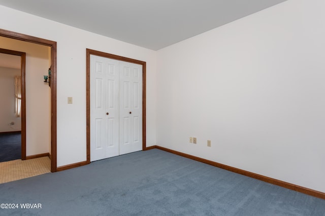 unfurnished bedroom featuring a closet and dark carpet