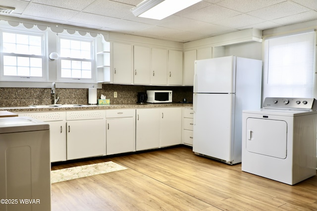 kitchen featuring white cabinetry, washer / clothes dryer, white appliances, and sink