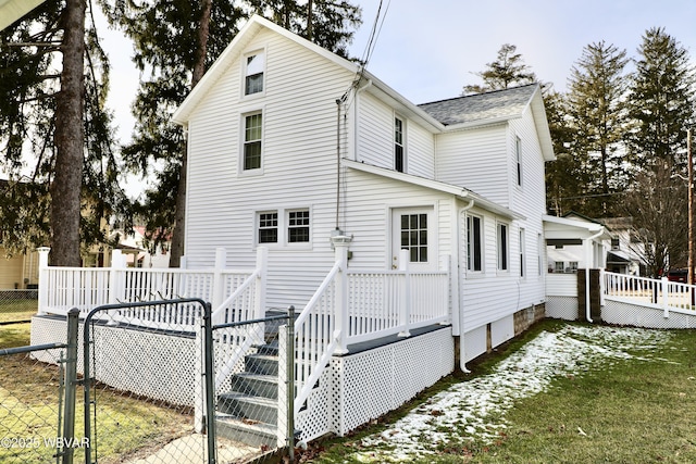 back of house with a deck and a lawn