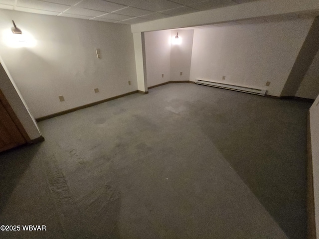 basement featuring a paneled ceiling, carpet floors, and a baseboard radiator