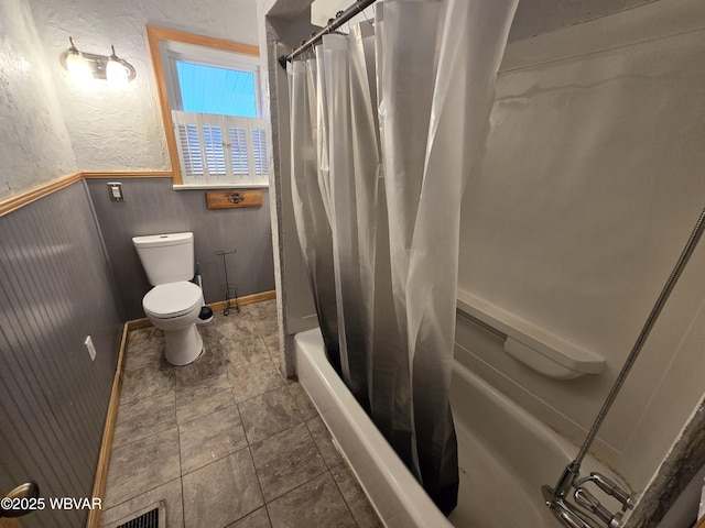 bathroom featuring shower / bath combination with curtain and toilet