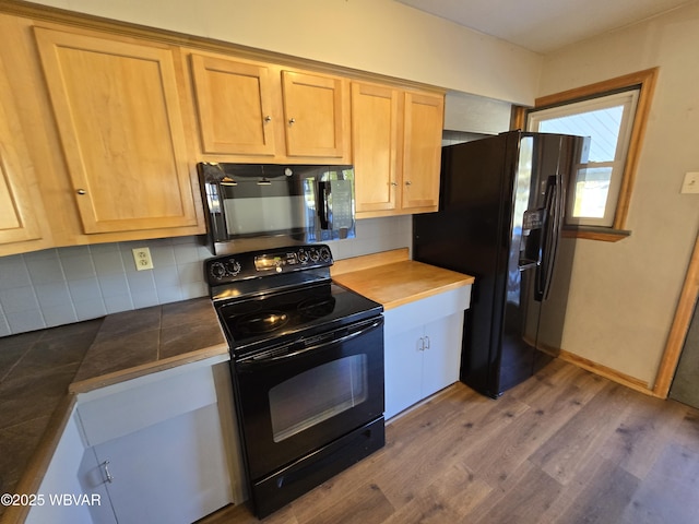 kitchen with black appliances, backsplash, hardwood / wood-style floors, and light brown cabinetry