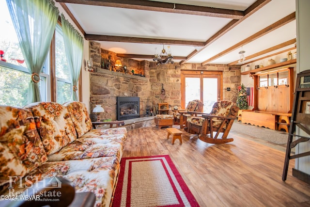 living room featuring beamed ceiling, wood-type flooring, a chandelier, and a fireplace