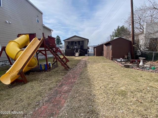 view of play area with a lawn, an outdoor structure, and fence