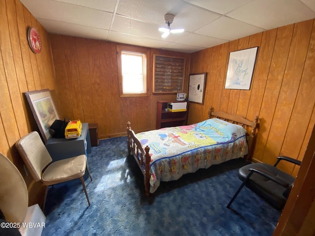 carpeted bedroom featuring a drop ceiling and wood walls