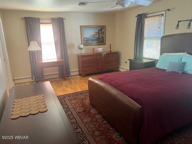 bedroom featuring light wood-type flooring, baseboards, and baseboard heating