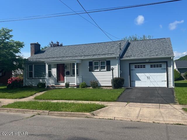 ranch-style home with covered porch, an attached garage, driveway, a front yard, and a chimney