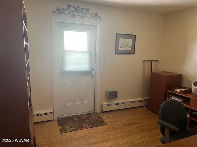 doorway with a baseboard heating unit, a baseboard radiator, wood finished floors, and a desk