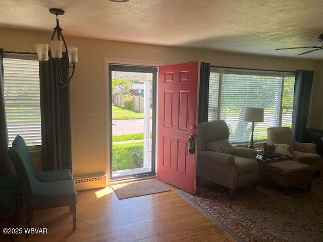 entrance foyer with a baseboard radiator, wood finished floors, ceiling fan, and a textured ceiling