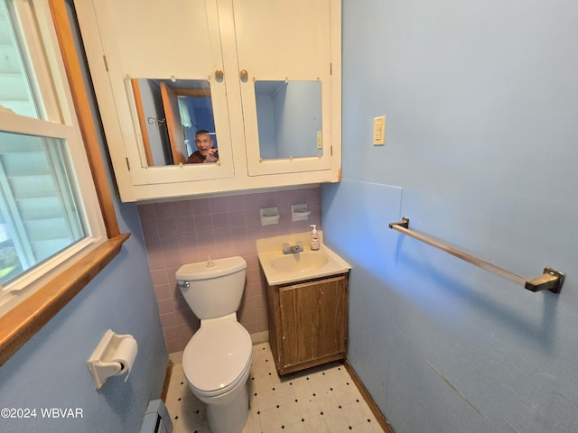 bathroom with vanity, a baseboard radiator, toilet, and tile walls