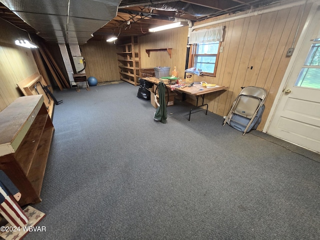 basement featuring wooden walls, carpet floors, and a healthy amount of sunlight