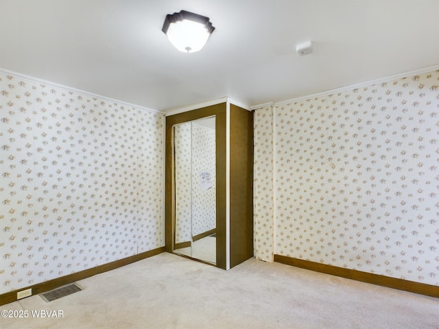 unfurnished bedroom featuring light colored carpet, a closet, and crown molding