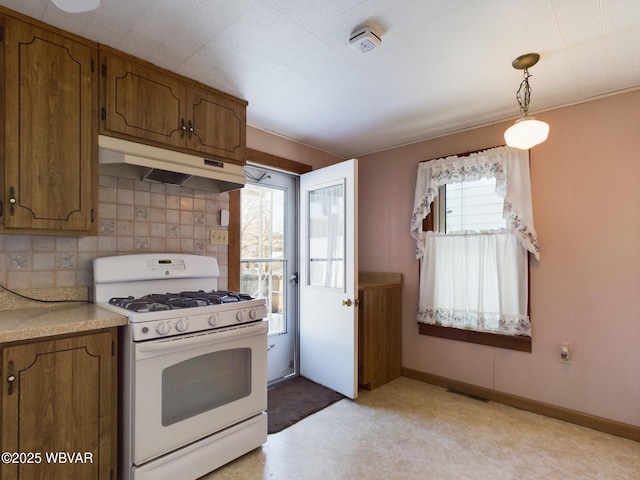 kitchen with decorative light fixtures, white range with gas cooktop, decorative backsplash, and a wealth of natural light