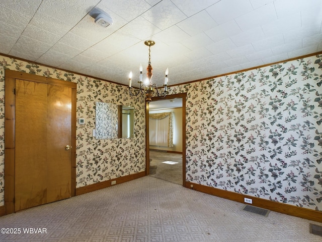 unfurnished room featuring carpet, crown molding, and an inviting chandelier