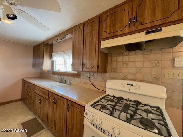 kitchen featuring ceiling fan, sink, backsplash, and white gas stove