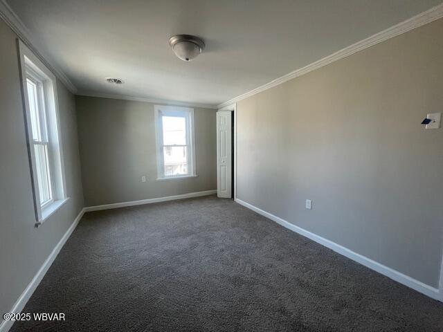 spare room featuring dark colored carpet, baseboards, and ornamental molding