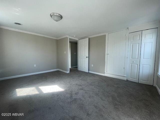 unfurnished bedroom featuring visible vents, multiple closets, carpet floors, crown molding, and baseboards