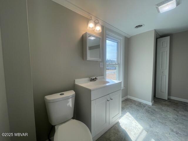 half bathroom featuring vanity, toilet, visible vents, and baseboards