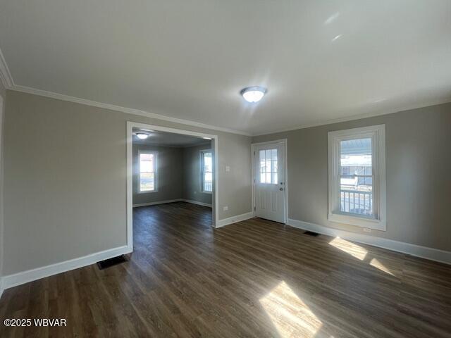 unfurnished room with visible vents, baseboards, dark wood finished floors, and crown molding