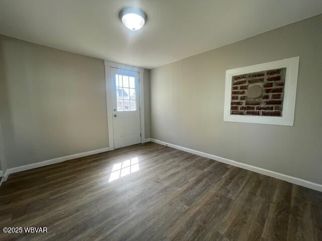 empty room with dark wood-type flooring and baseboards