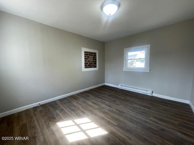 empty room with dark wood-style floors, baseboards, and baseboard heating