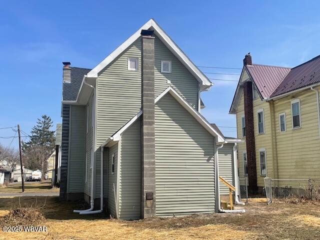 view of property exterior with a chimney and fence