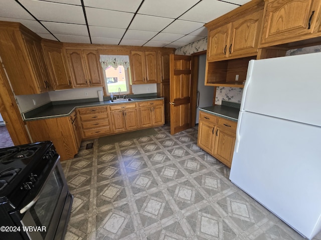 kitchen featuring black range oven, a paneled ceiling, sink, and white fridge