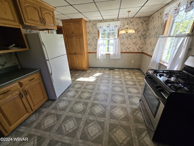 kitchen with a paneled ceiling, an inviting chandelier, white refrigerator, decorative light fixtures, and gas stove