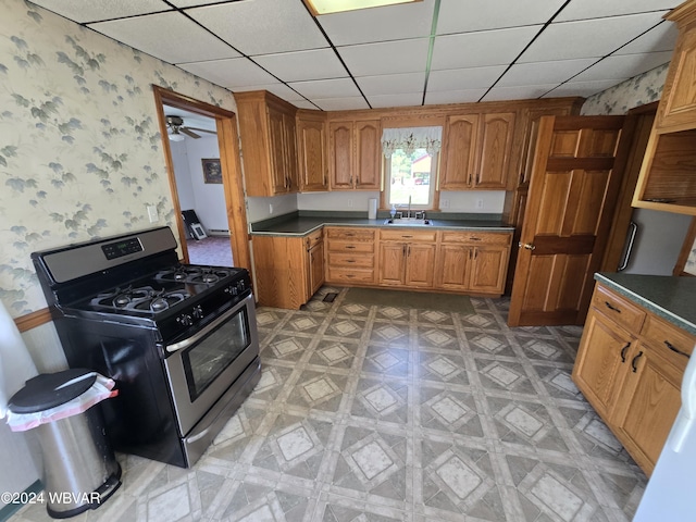 kitchen featuring a paneled ceiling, ceiling fan, sink, and stainless steel range with gas stovetop