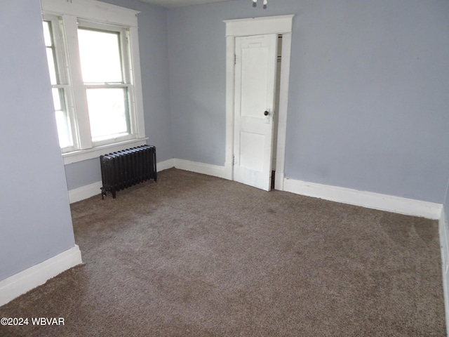 carpeted empty room featuring radiator heating unit