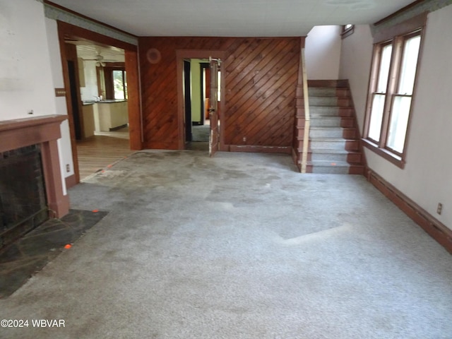 unfurnished living room featuring wood walls and light carpet