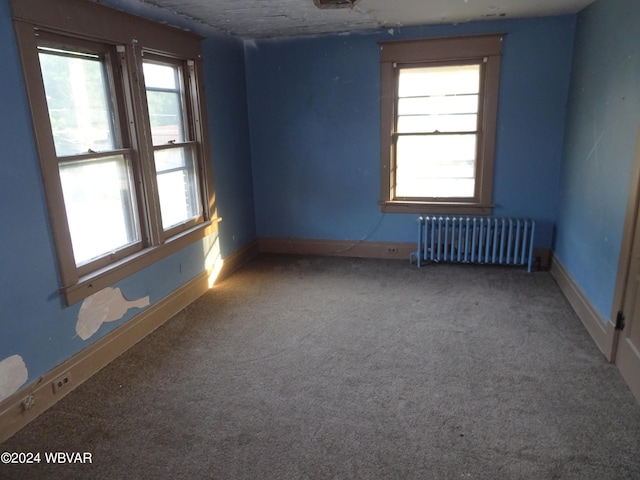 spare room with carpet flooring and radiator heating unit