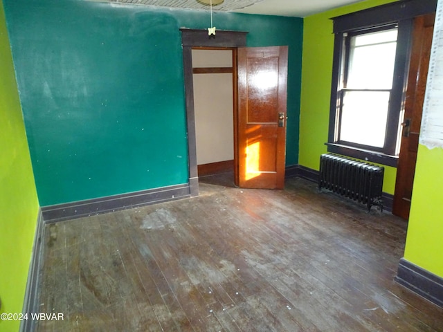 unfurnished bedroom featuring radiator heating unit and hardwood / wood-style flooring