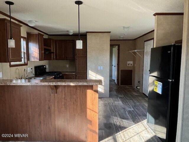 kitchen with black appliances, a kitchen breakfast bar, crown molding, dark hardwood / wood-style flooring, and kitchen peninsula